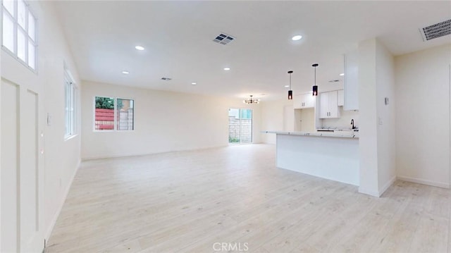 kitchen featuring visible vents, open floor plan, light countertops, white cabinetry, and pendant lighting