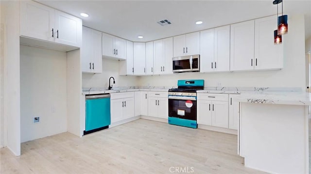 kitchen with pendant lighting, appliances with stainless steel finishes, light wood-type flooring, and white cabinets