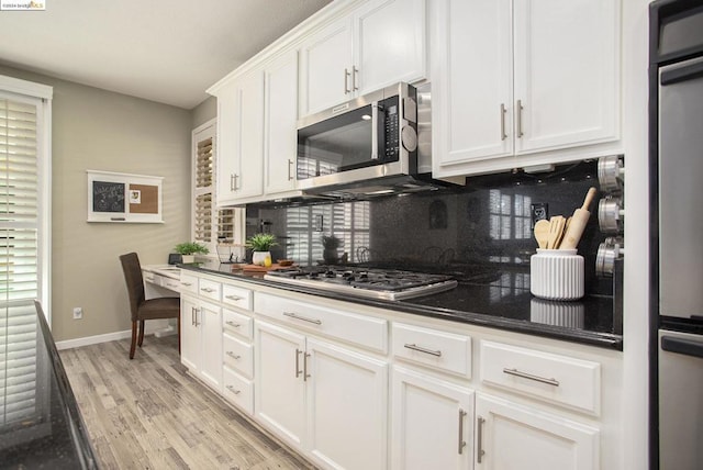 kitchen with white cabinetry, appliances with stainless steel finishes, light hardwood / wood-style floors, and decorative backsplash