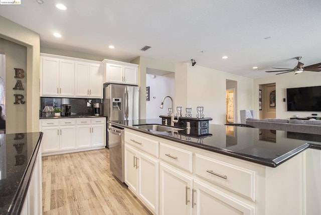 kitchen featuring appliances with stainless steel finishes, sink, dark stone countertops, white cabinets, and light hardwood / wood-style floors