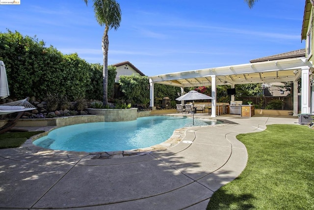 view of swimming pool featuring exterior kitchen, a patio area, and a lawn