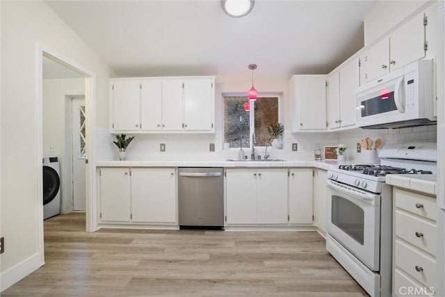 kitchen with white appliances, washer / clothes dryer, white cabinetry, sink, and pendant lighting