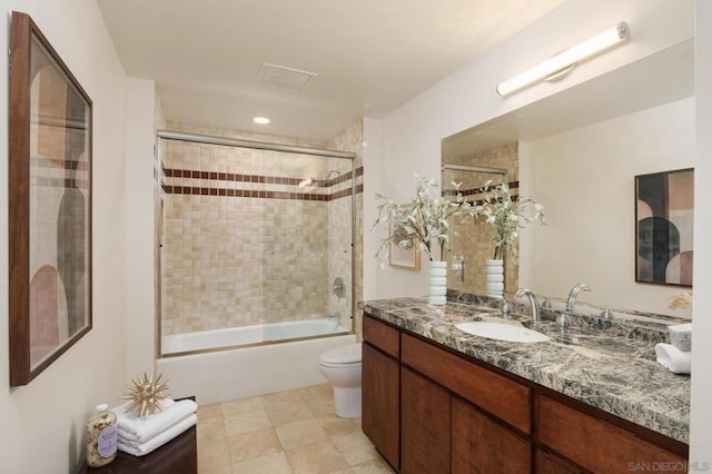 full bathroom featuring vanity, shower / bath combination with glass door, and toilet