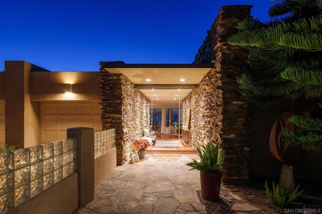 patio at twilight with french doors, a garage, and a porch