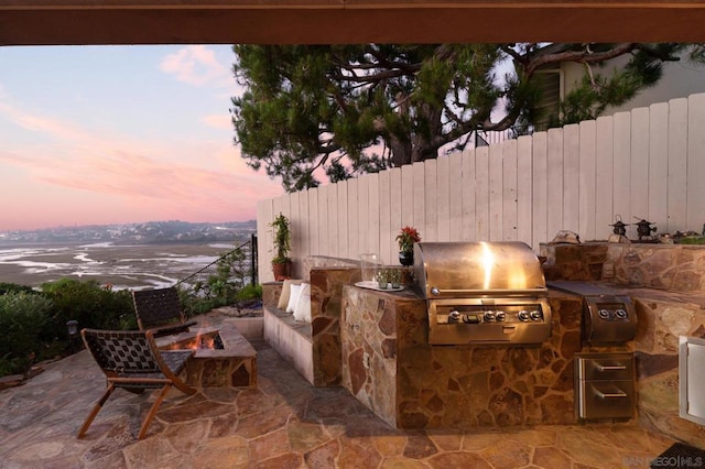 patio terrace at dusk featuring area for grilling and exterior kitchen