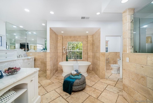 bathroom with vanity, a tub, tile walls, and toilet