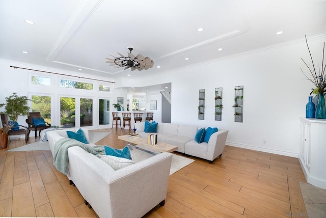 living room with ornamental molding, light hardwood / wood-style floors, a raised ceiling, and ceiling fan