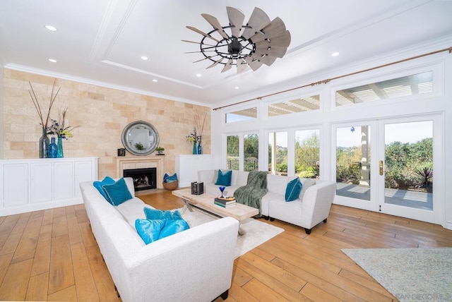 living room featuring crown molding, a wealth of natural light, and light hardwood / wood-style flooring