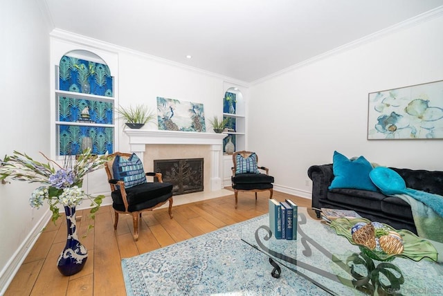 living room with built in shelves, a fireplace, hardwood / wood-style floors, and crown molding