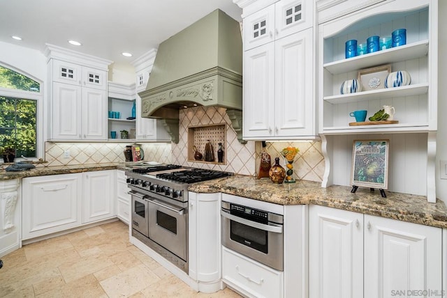 kitchen with white cabinetry, dark stone counters, stainless steel appliances, and custom range hood