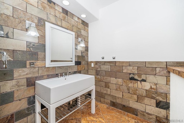 bathroom featuring sink and tile walls