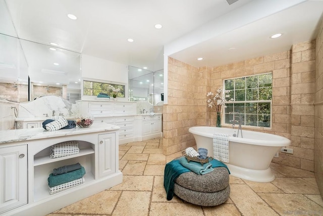 bathroom featuring vanity, tile walls, decorative backsplash, and a washtub