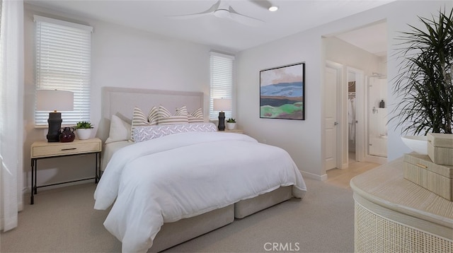 bedroom featuring multiple windows, light carpet, ensuite bathroom, and ceiling fan