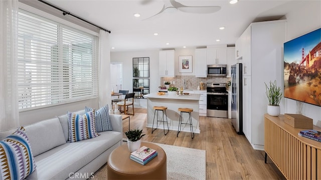 living room with ceiling fan, sink, and light hardwood / wood-style floors