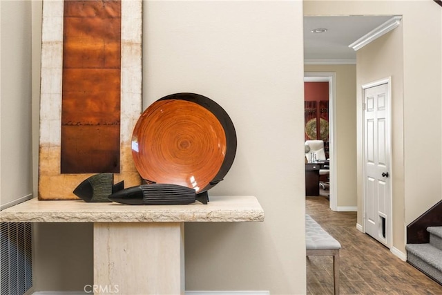 interior details featuring wood finished floors, baseboards, visible vents, built in study area, and ornamental molding