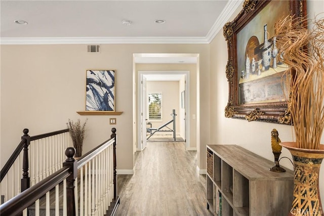 corridor with visible vents, crown molding, baseboards, an upstairs landing, and wood finished floors