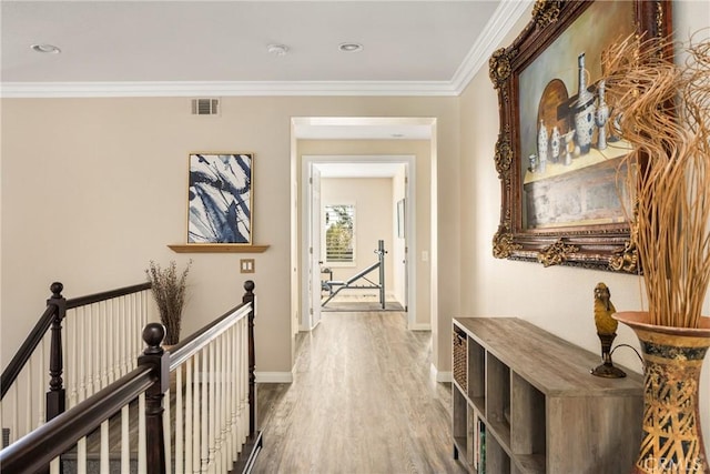 corridor with crown molding, visible vents, baseboards, and wood finished floors