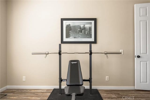 exercise room with baseboards and wood finished floors