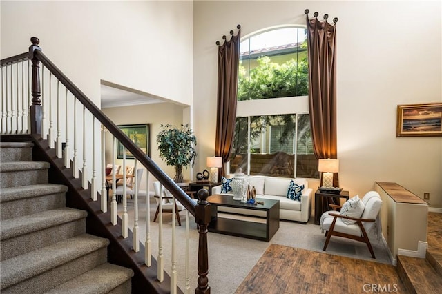 stairway featuring a towering ceiling, baseboards, and crown molding
