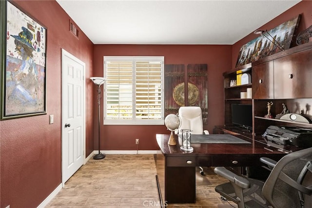 office area with visible vents, baseboards, and wood finished floors