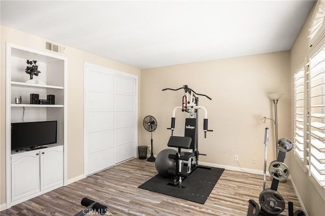 exercise room featuring visible vents, baseboards, and wood finished floors