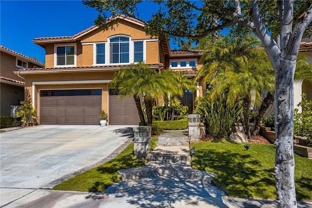 mediterranean / spanish-style house with stucco siding, an attached garage, a tile roof, and driveway