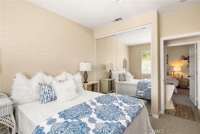 carpeted bedroom with visible vents, a closet, and baseboards