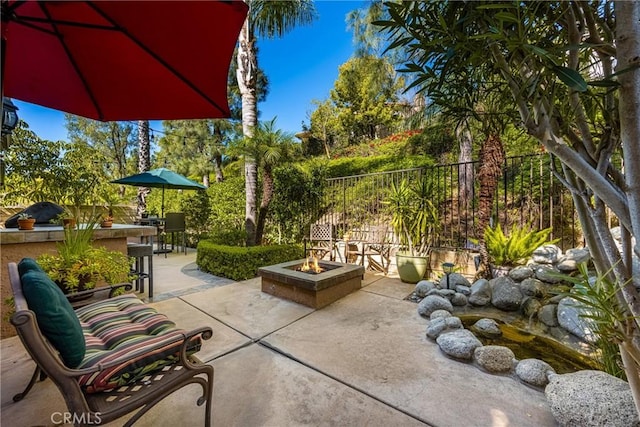 view of patio with an outdoor fire pit, outdoor dining area, and fence