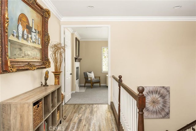 hallway with an upstairs landing, baseboards, wood finished floors, and ornamental molding