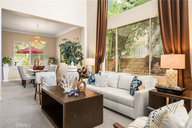 living area featuring an inviting chandelier, crown molding, carpet, and baseboards