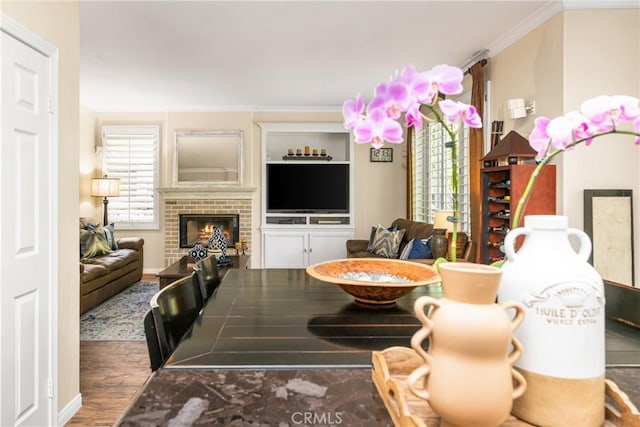 dining space with wood finished floors, a fireplace, ornamental molding, and a healthy amount of sunlight