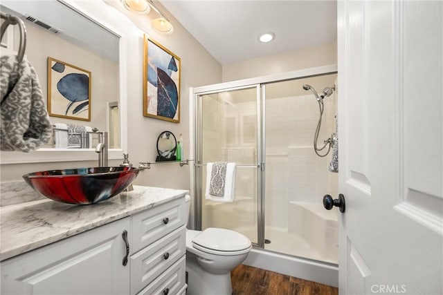 bathroom featuring vanity, wood finished floors, visible vents, and a stall shower