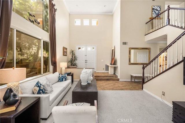 carpeted living area with baseboards, visible vents, a high ceiling, and crown molding