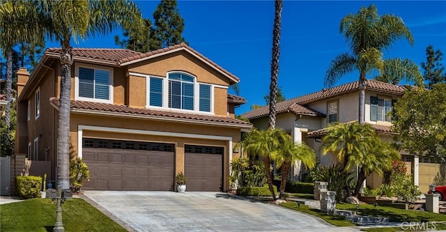 mediterranean / spanish house with a tiled roof, driveway, a garage, and stucco siding