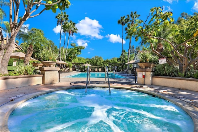 community pool featuring a patio and a hot tub