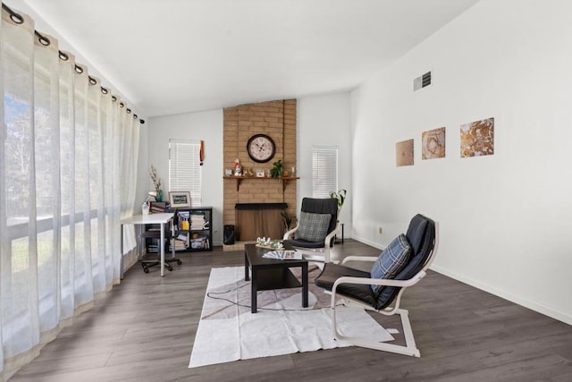 sitting room featuring dark hardwood / wood-style flooring, vaulted ceiling, and a brick fireplace