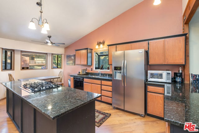 kitchen featuring lofted ceiling, light hardwood / wood-style flooring, stainless steel appliances, sink, and a center island