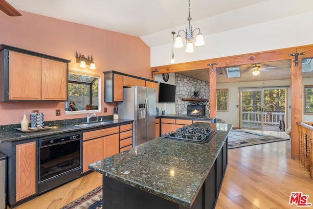 kitchen featuring lofted ceiling, light hardwood / wood-style flooring, stainless steel appliances, sink, and a center island