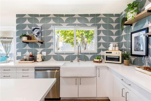 kitchen with decorative backsplash, white cabinetry, stainless steel dishwasher, and sink