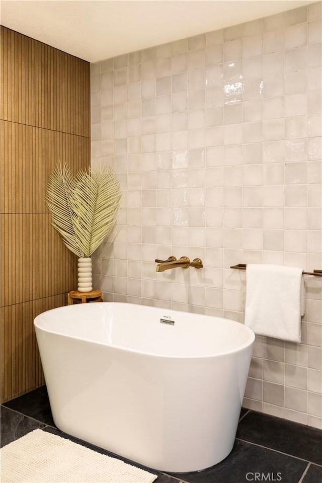 bathroom with tile patterned floors, a bathing tub, and tile walls