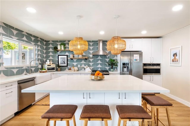 kitchen with a center island, white cabinetry, exhaust hood, and appliances with stainless steel finishes