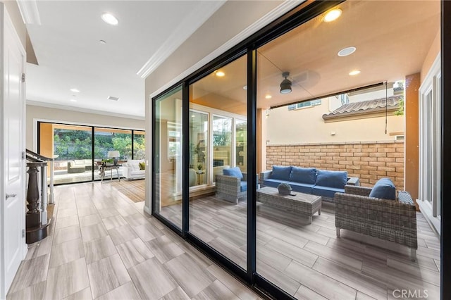 doorway to outside with light hardwood / wood-style floors, brick wall, and ornamental molding