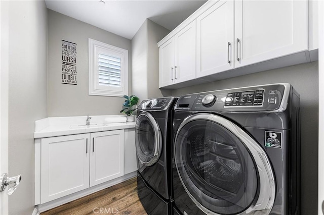 clothes washing area with dark wood-type flooring, sink, cabinets, and independent washer and dryer