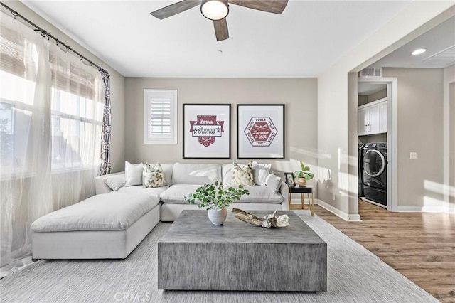 living room with ceiling fan, light wood-type flooring, and washer / dryer