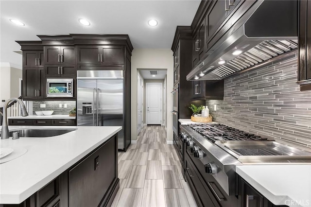 kitchen featuring sink, stainless steel appliances, backsplash, extractor fan, and light wood-type flooring