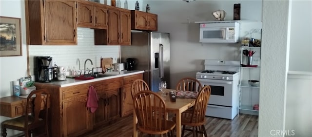 kitchen featuring white appliances, tasteful backsplash, wood-type flooring, and sink