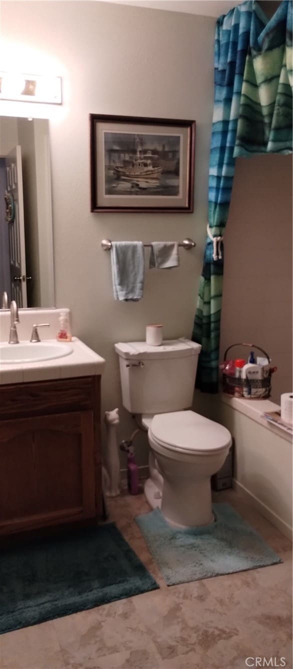 bathroom featuring vanity, curtained shower, and toilet