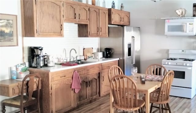 kitchen featuring white appliances, light countertops, a sink, and light wood finished floors