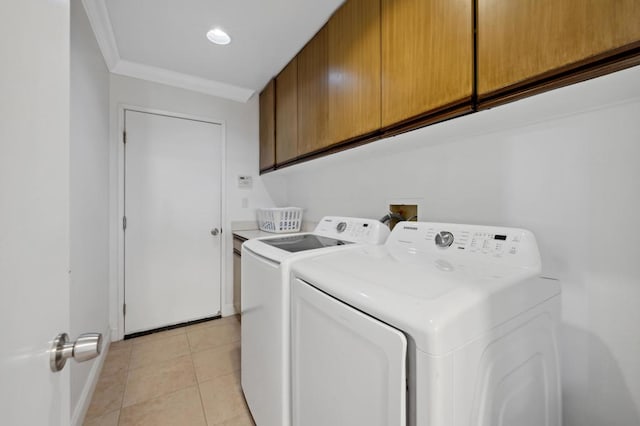 washroom with light tile patterned floors, washing machine and dryer, cabinets, and ornamental molding