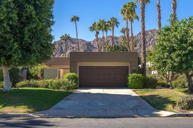 view of front of property featuring a front yard, a garage, and a mountain view